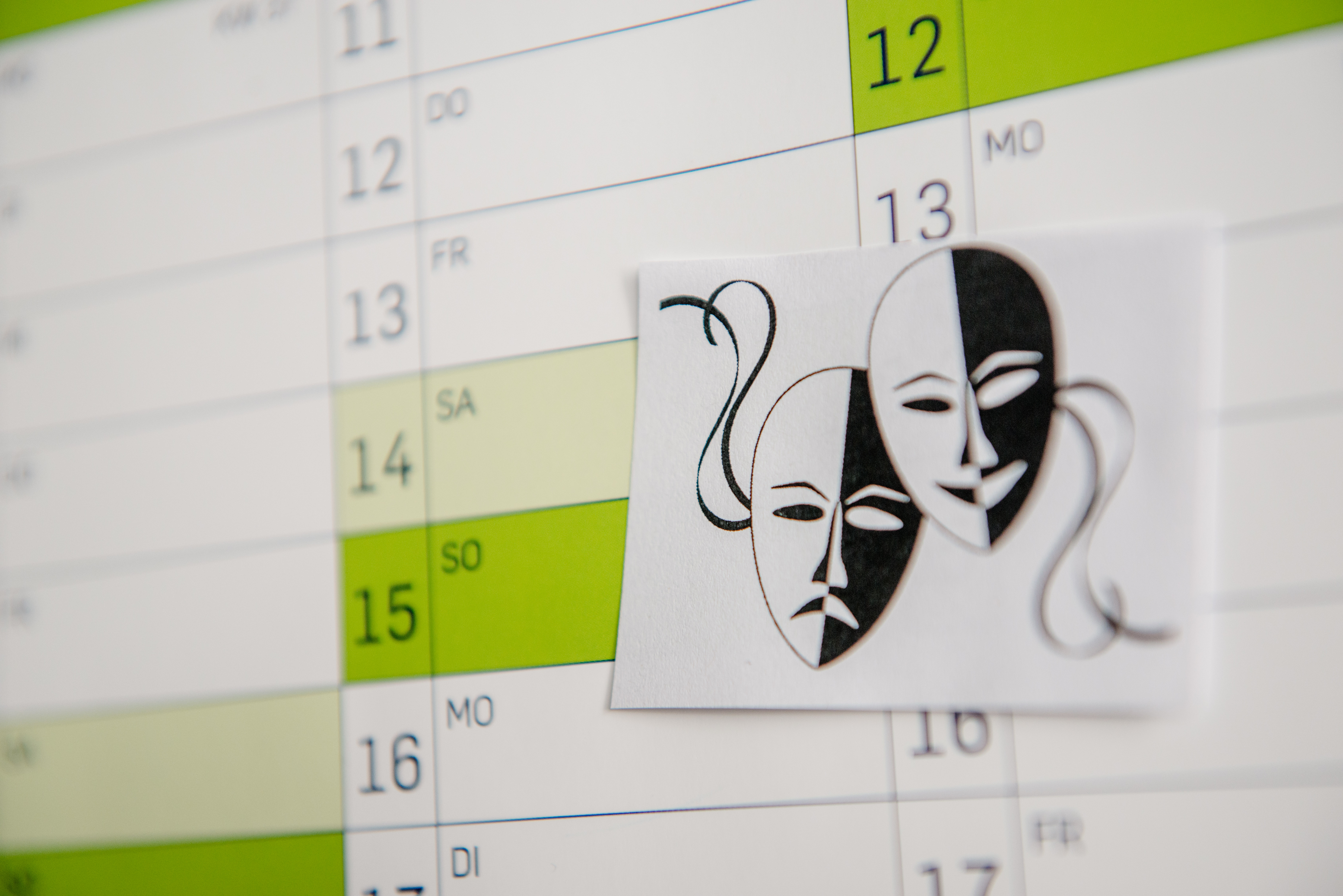 Zwei Theatermasken als Merkzettel an einem Wandkalender