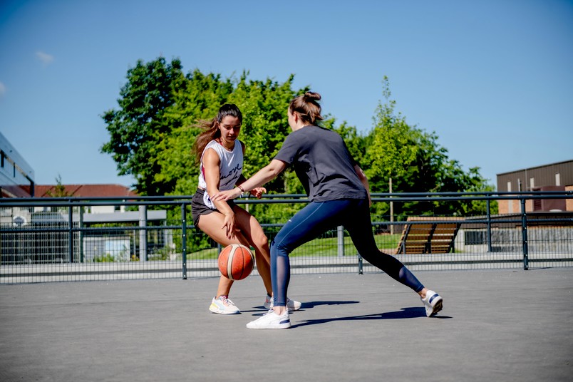 Zwei Studentinnen spielen draußen Basketball