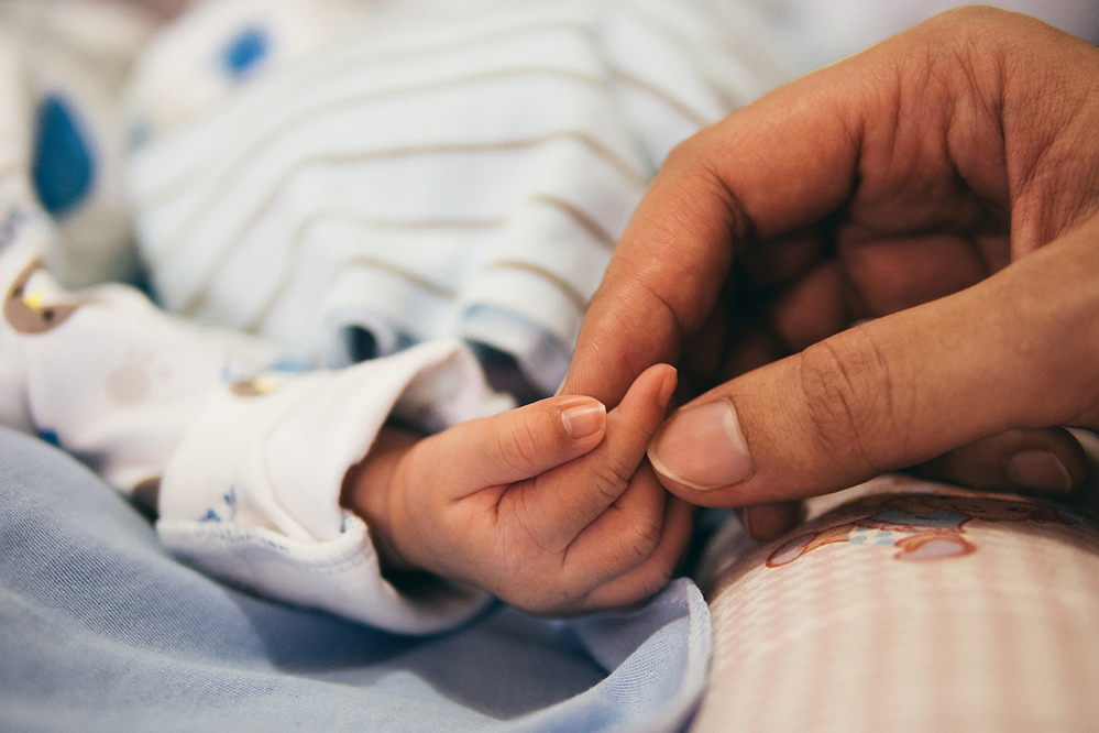 Eine Hand hält den Finger eines Babys